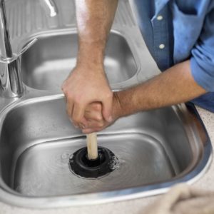 Plumber unclogging a kitchen sink