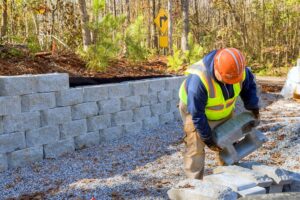 Construction worker is currently working on building retaining wall while constructing wall a