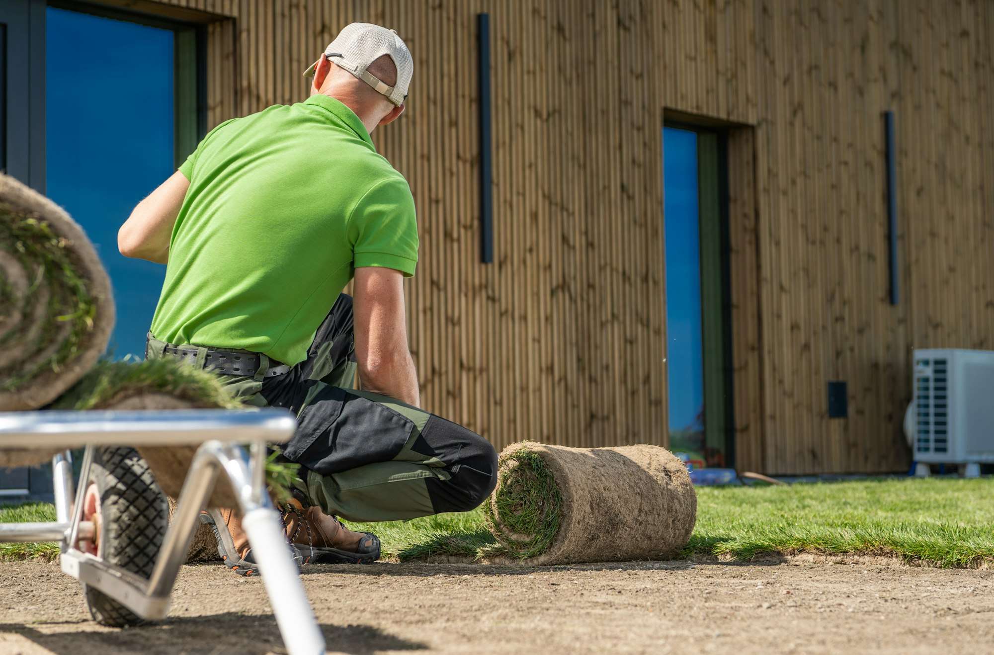 Gardener installing new grass turfs in front of a house.