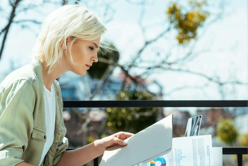 blonde businesswoman sitting on terrace with folder and papers