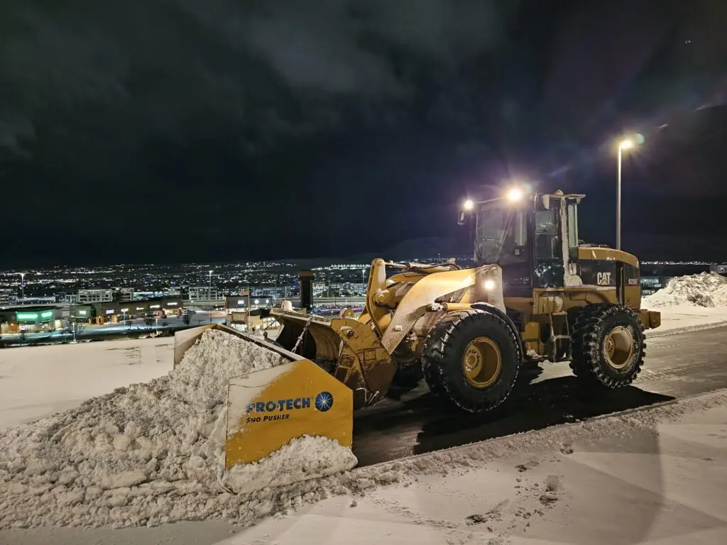 Front loader moving snow from a commercial parking area