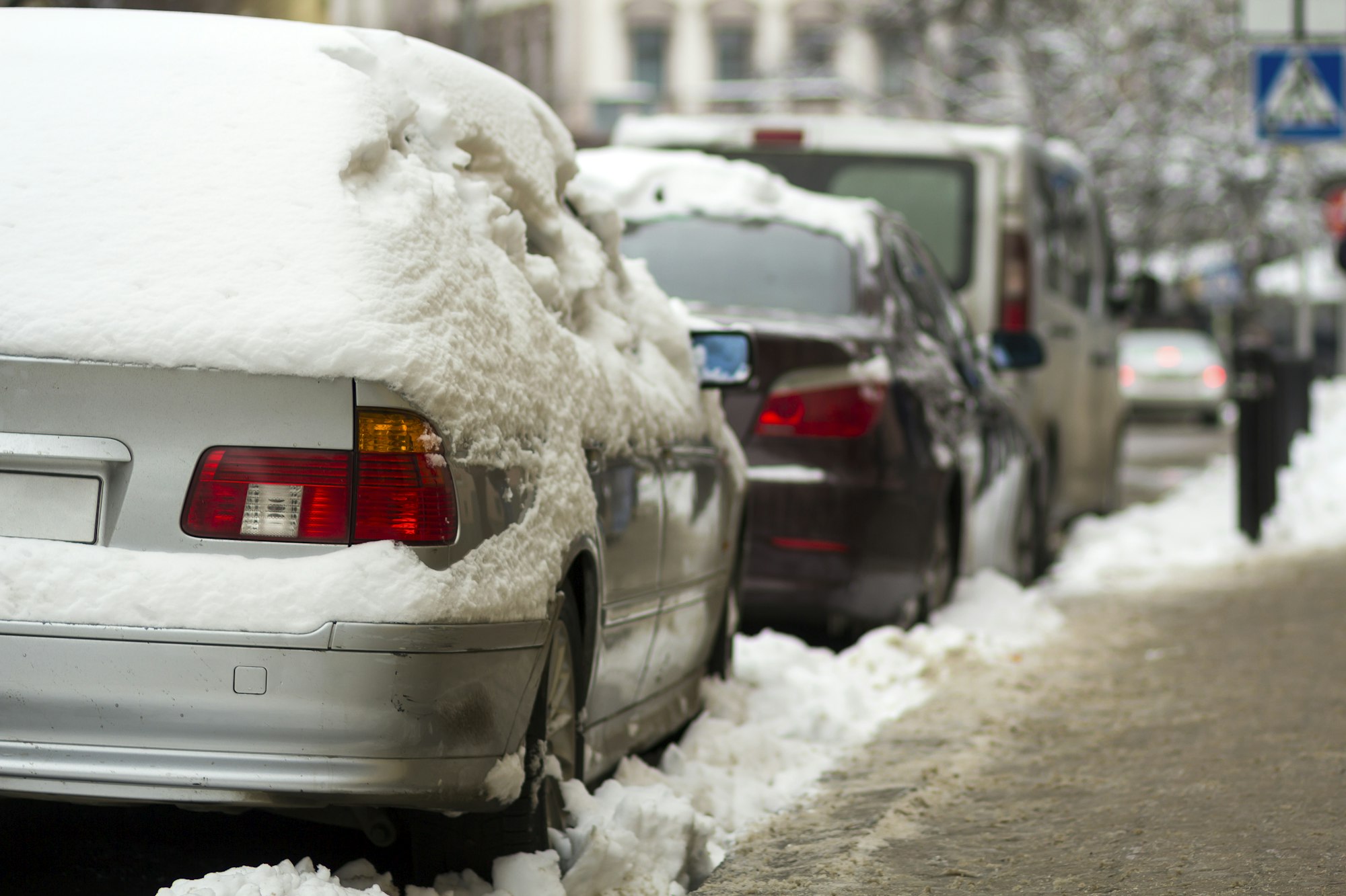 Cars covered in snow on a parking lot in city area after winter ...