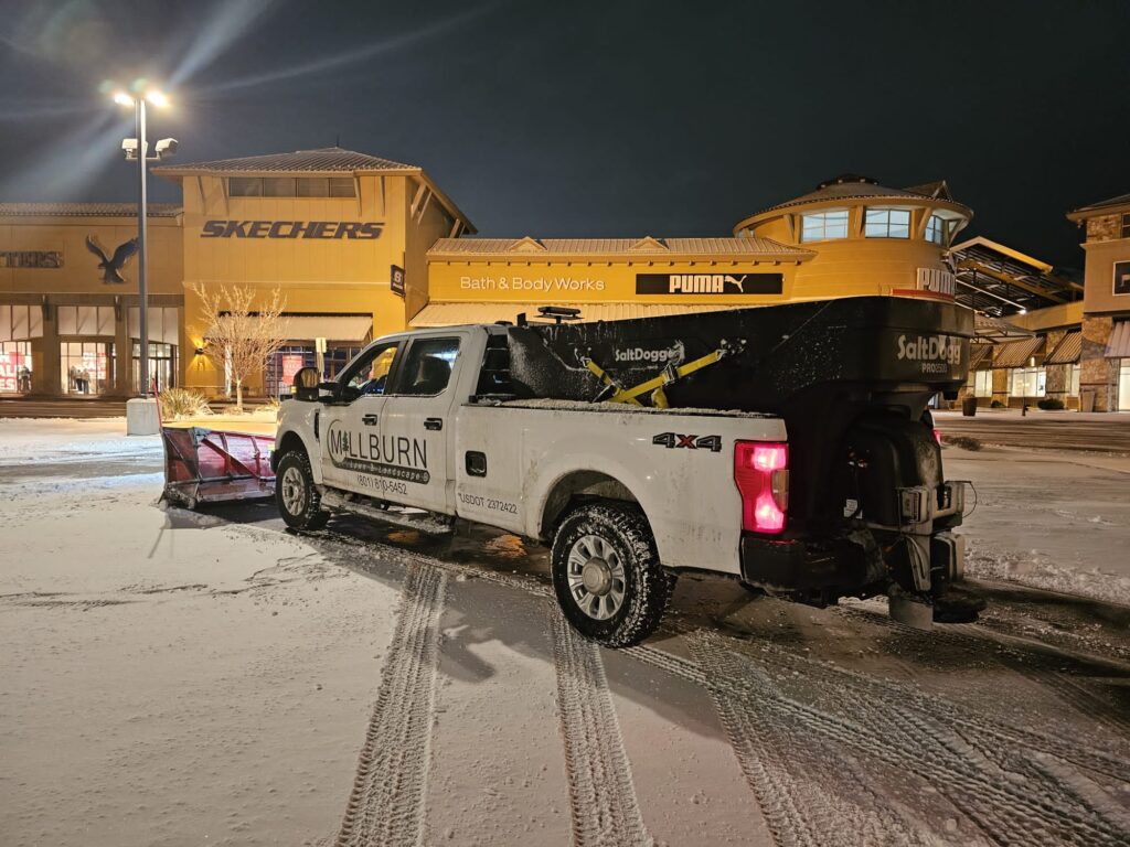 Millburn snow removal vehicle spreading salt and gravel in salt lake city parking Lot