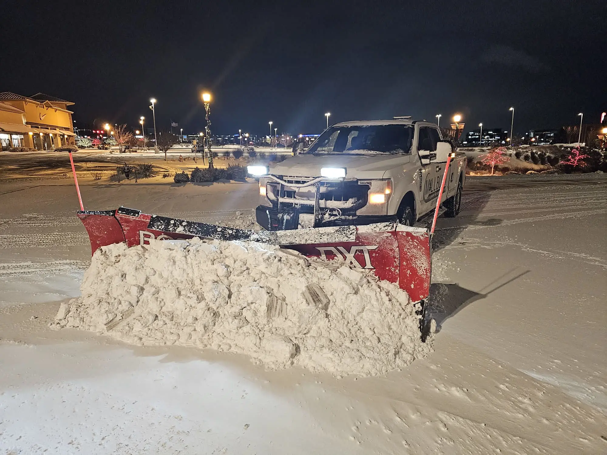 Commercial snow removal crew operating plows and salt spreaders at 3 A.M. in Salt Lake City, preparing a business property before sunrise.