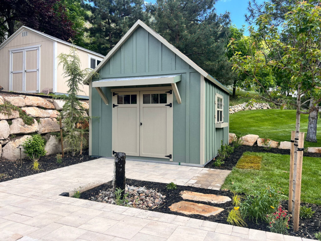 Custom backyard garden shed with paver walkway, landscaped planting beds, and manicured lawn