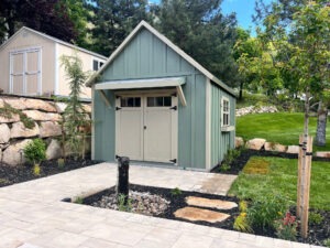 Custom backyard garden shed with paver walkway, landscaped planting beds, and manicured lawn