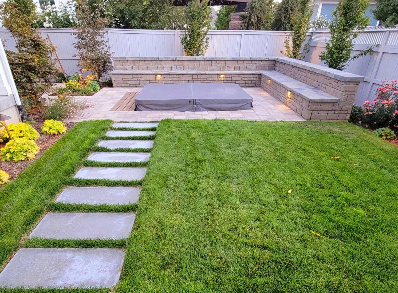 A dense row of Emerald Green Arborvitae trees forming a tall privacy hedge along a suburban Utah backyard fence line
