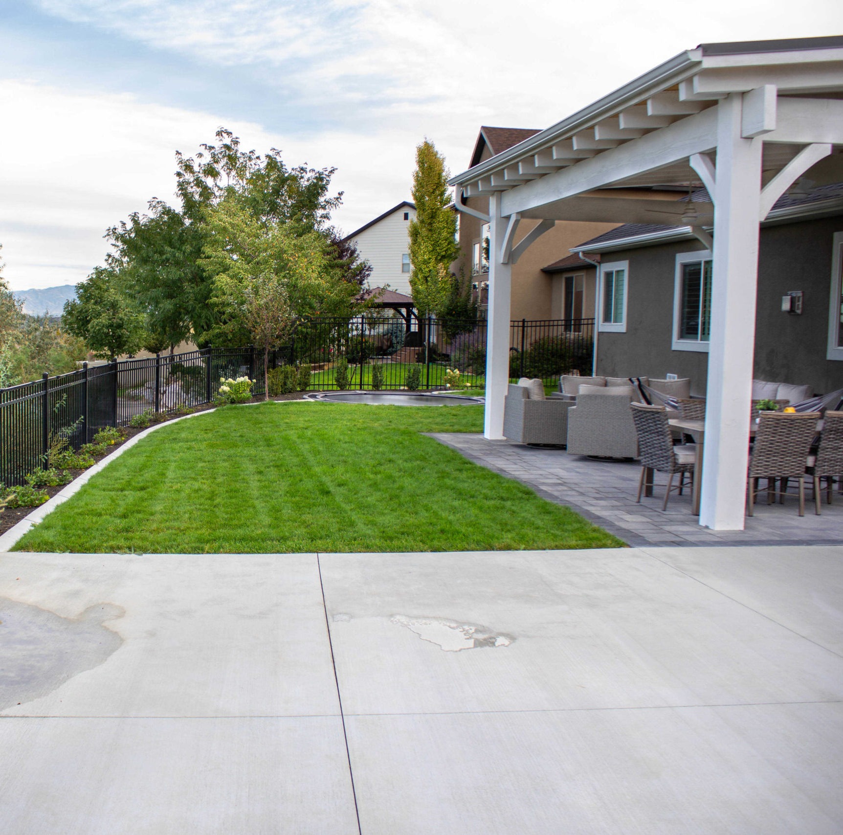 A premium large-format porcelain paver patio in a Herriman Utah backyard with powder-coated aluminum pergola and Oquirrh Mountain views