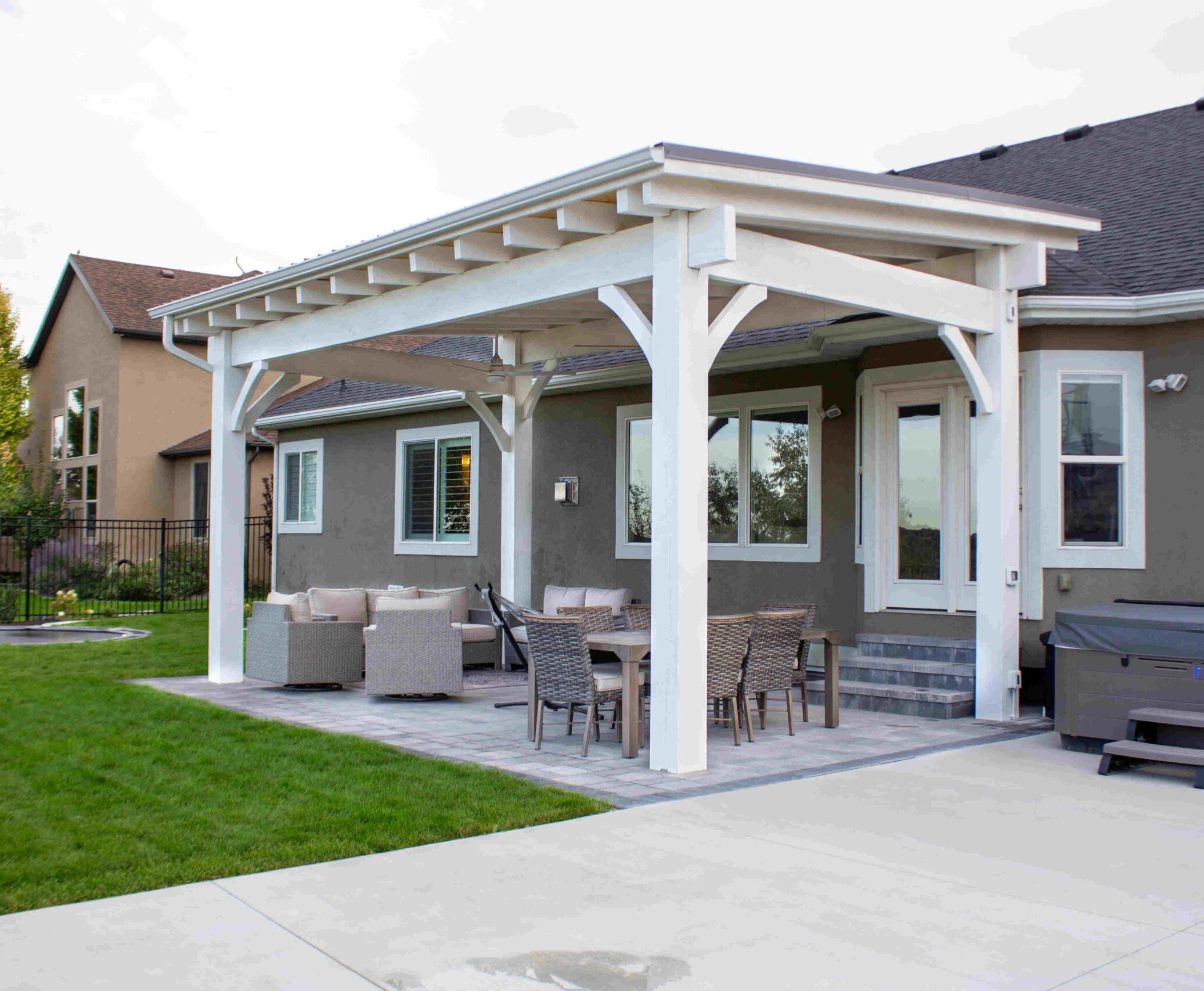 A beautifully designed and HOA-compliant backyard patio with pergola in South Jordan Utah featuring neutral-toned pavers and lush landscaping