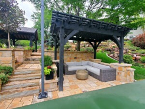 A South Jordan Utah backyard patio showing the perfect balance of beautiful stone pavers, a louvered pergola, outdoor kitchen, and lush drought-tolerant landscaping