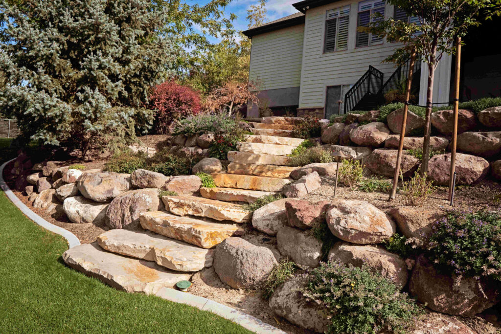 Custom retaining wall transforming a sloped backyard in Bluffdale, Utah into a beautiful terraced landscape with usable outdoor space.