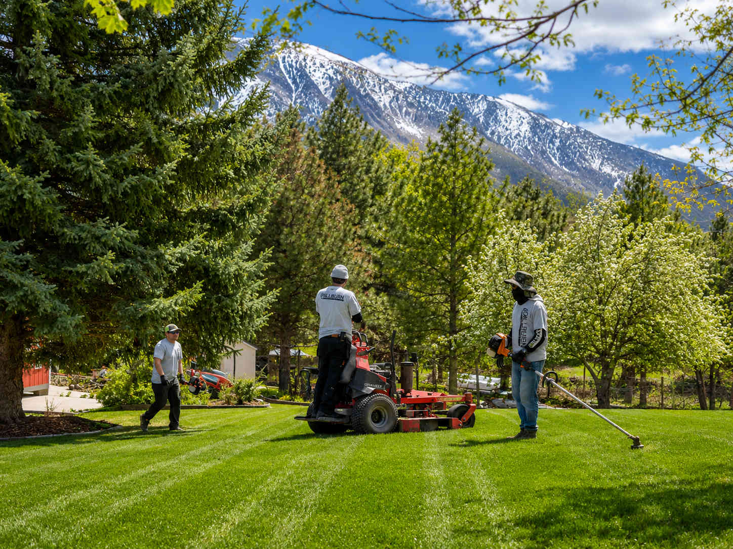 Millburn Lawn & Landscape professional crew mowing a well-maintained lawn in an Eagle Mountain Utah neighborhood with Utah County mountains visible