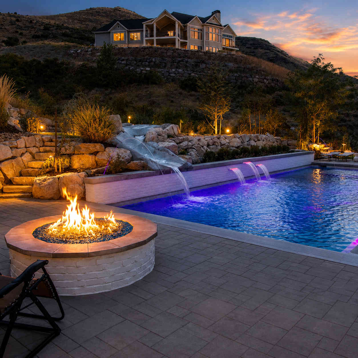 A Millburn Lawn & Landscape completed Eagle Mountain Utah backyard featuring engineered block retaining walls, concrete paver patio and Cedar Valley mountain views