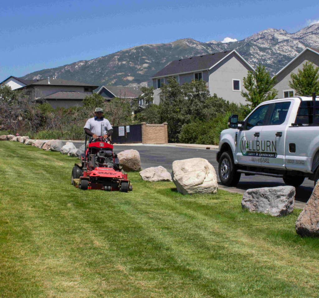 A professional landscaping crew maintaining HOA common area grounds in a Saratoga Springs Utah neighborhood with mountain views