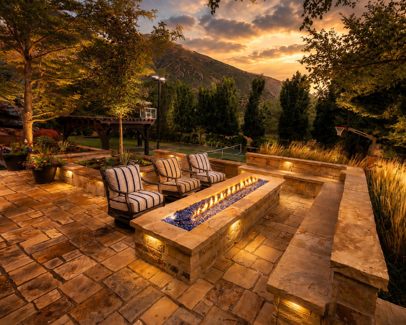 Covered outdoor living space at dusk in Eagle Mountain with linear gas fireplace, outdoor TV, kitchen, and wicker seating — Millburn Lawn & Landscape