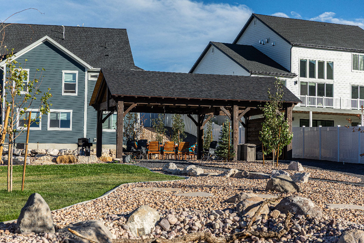 A Millcreek Utah small urban backyard designed with defined outdoor zones a pergola structure and layered planting that makes the space feel twice its actual size